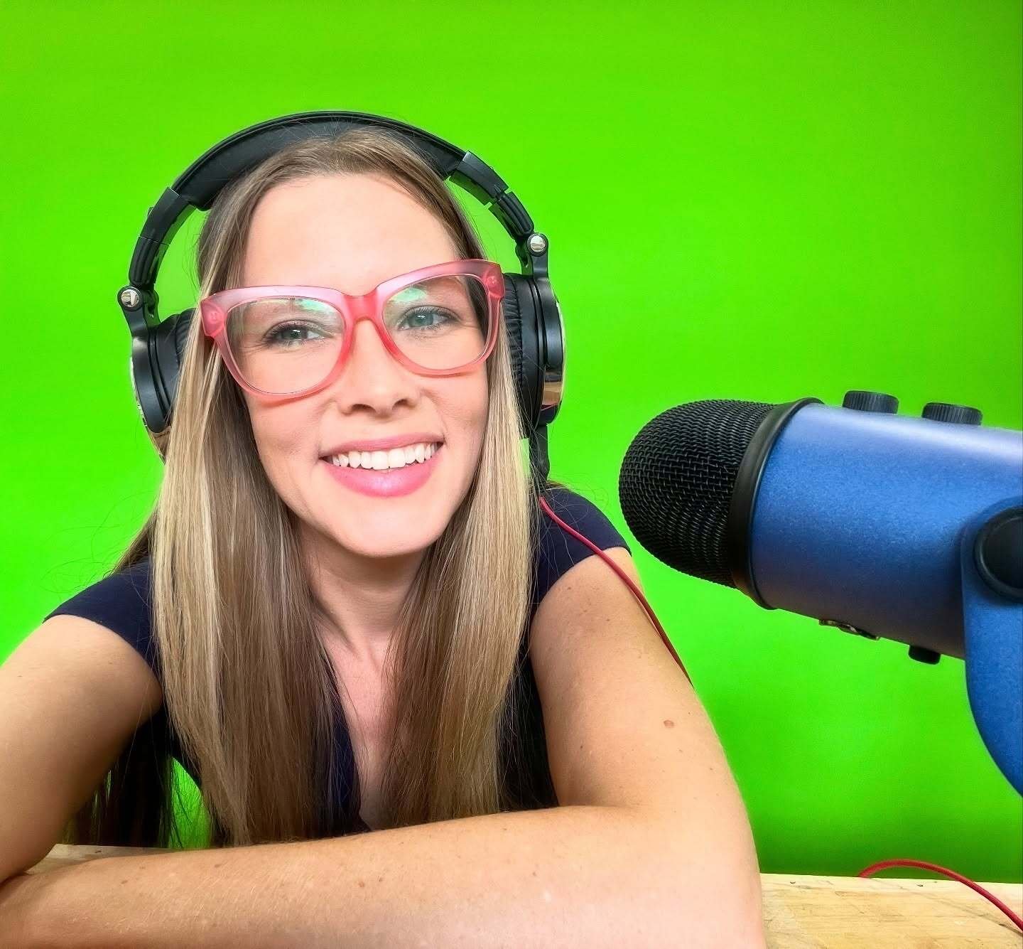Casey Byrus wearing headphones and speaking into a microphone in front of a green screen while recording content